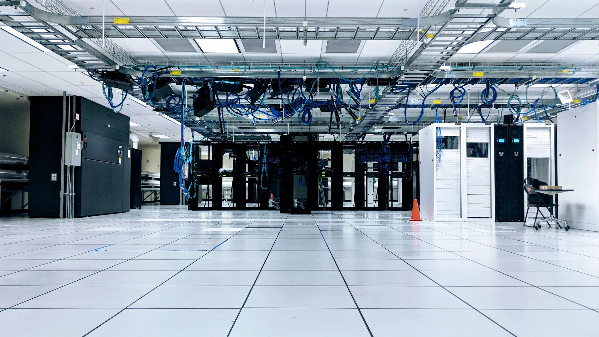 Raised-floor data hall with server racks and overhead cable trays