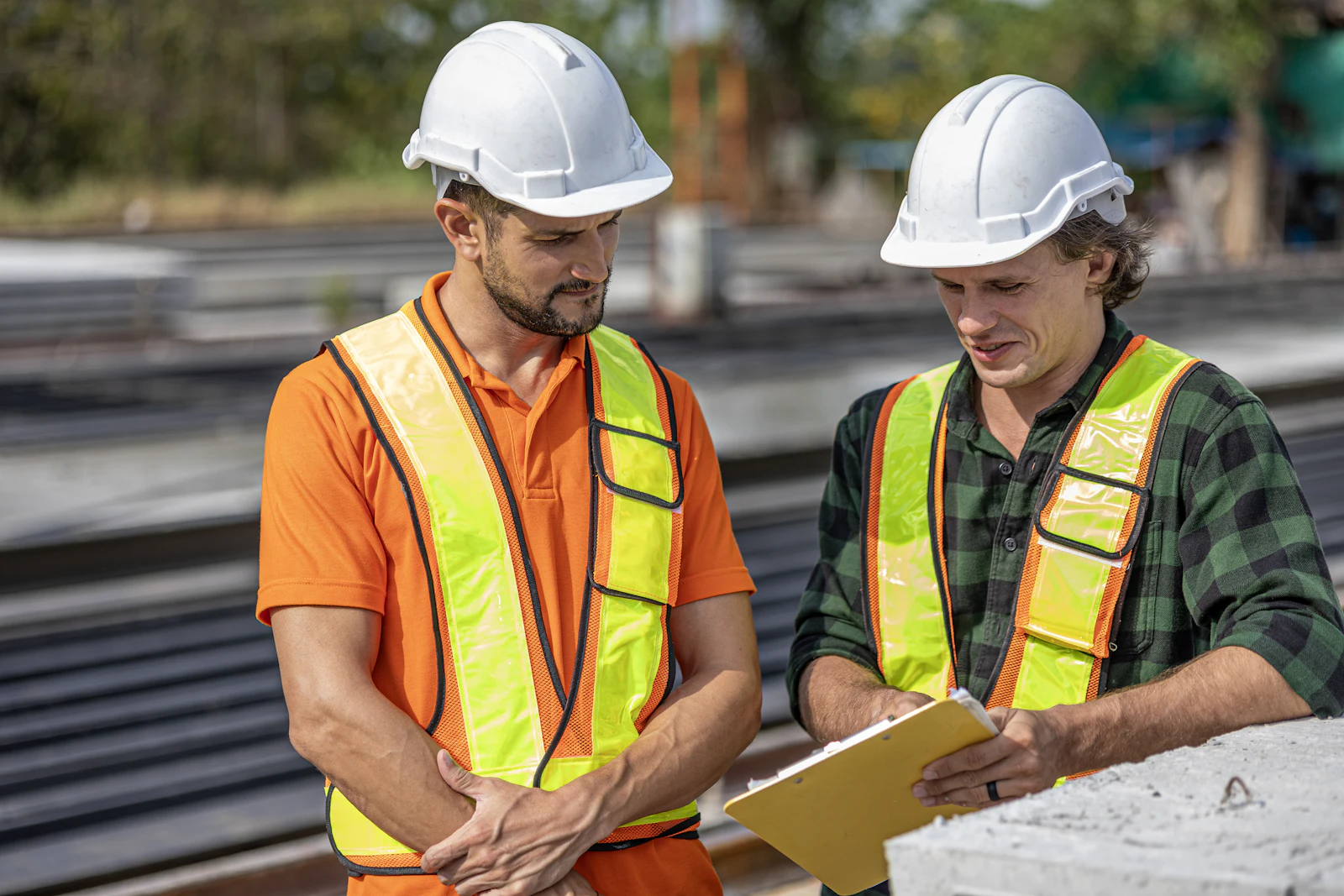 Two field leaders in hard hats reviewing plans on a job site