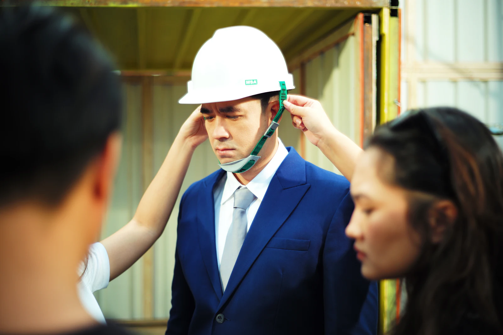 Executive in a suit fitting a white hard hat before a site walk